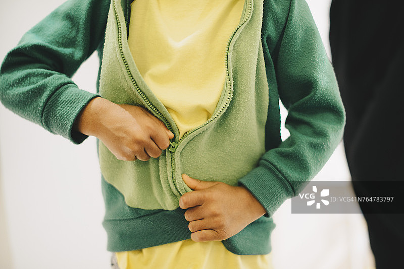 男孩在家拉上夹克的身体中部图片素材