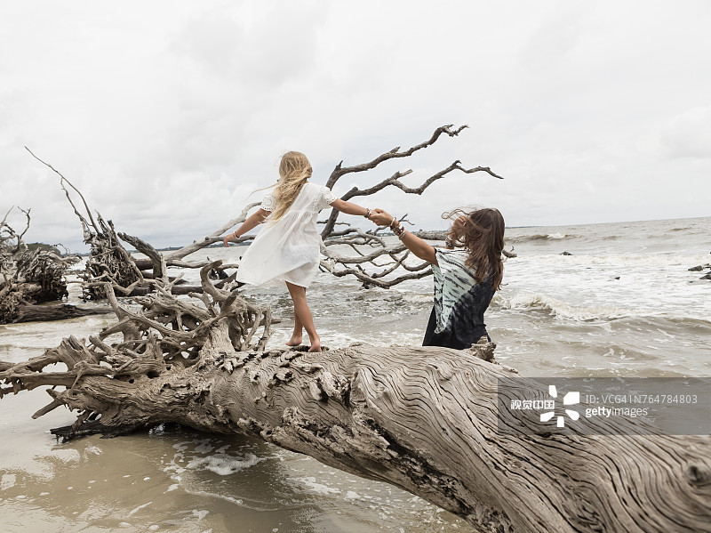 在海滩上走在浮木上的白人母女图片素材