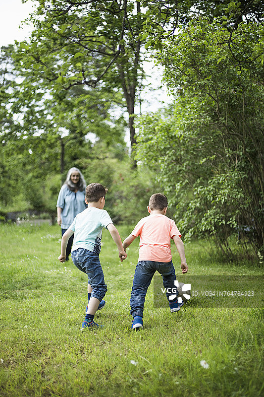 祖母看着双胞胎男孩在后院踢足球图片素材