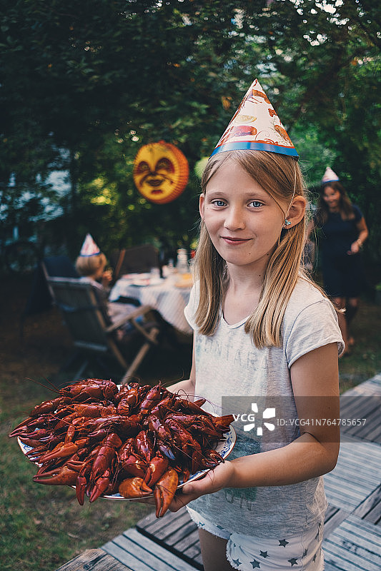 女孩在花园晚宴上手持一盘小龙虾图片素材