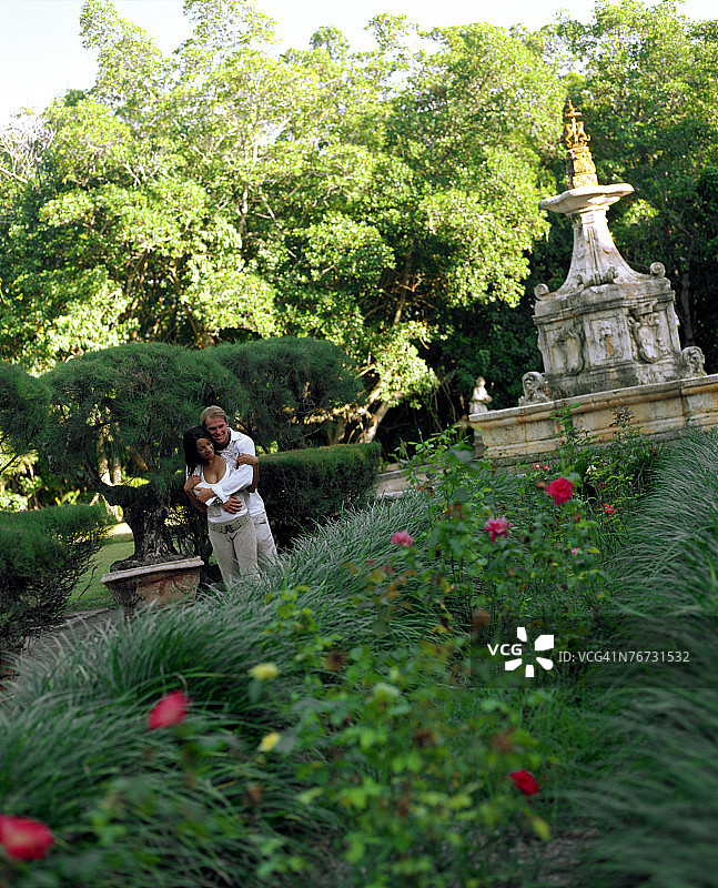 情侣在花园喷泉旁拥抱图片素材