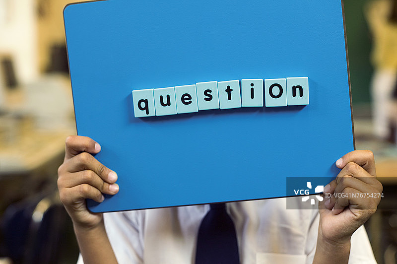 男孩举起磁性板上的问号图片素材