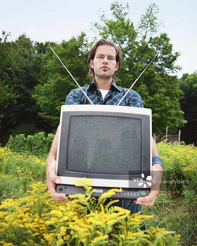 男子在田野里拿着电视机图片素材