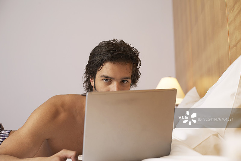 在床上使用笔记本电脑的男人图片素材
