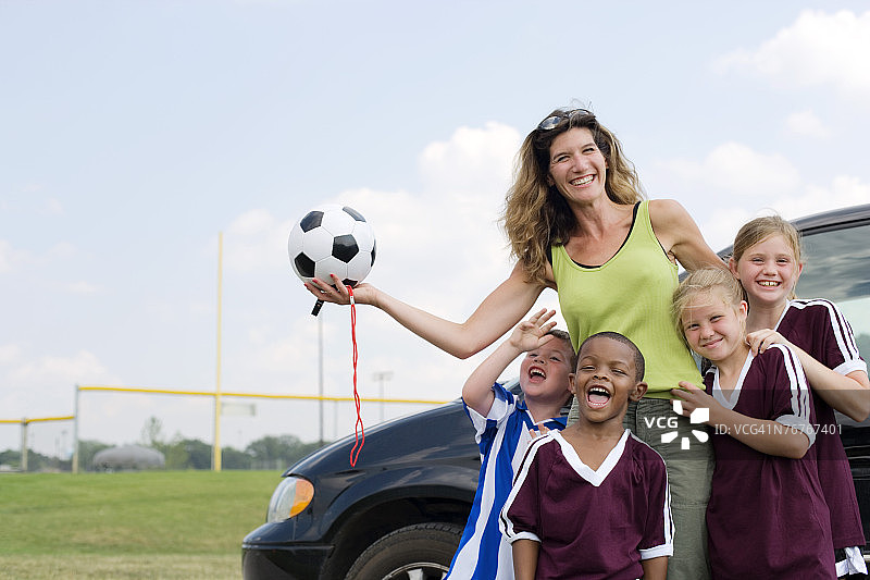 穿着足球队服的女人和孩子们在货车旁拥抱图片素材