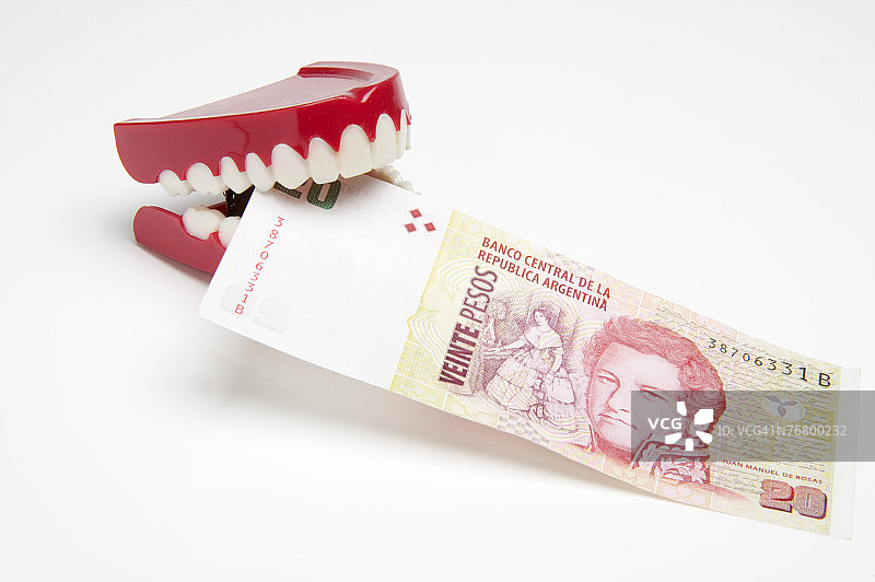 虚假牙齿啃食阿根廷比索图片素材