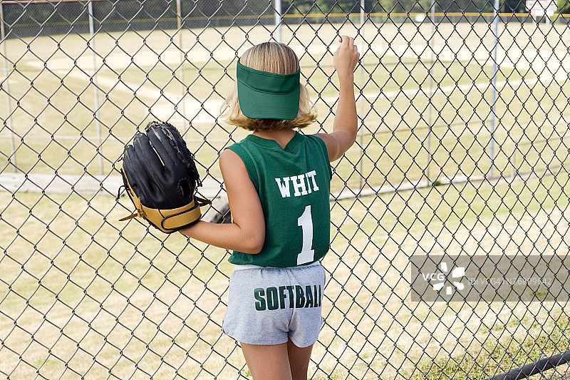 穿着棒球服站在栅栏旁的女孩图片素材