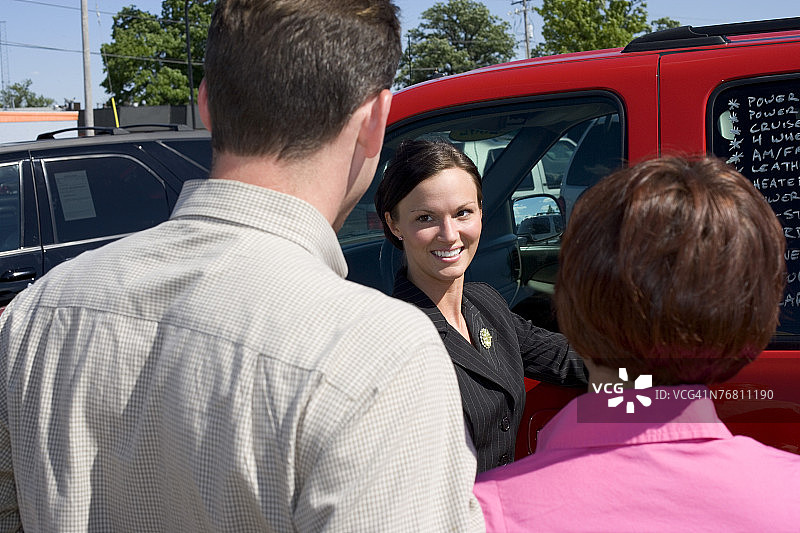 女售货员和一对夫妇在SUV旁图片素材
