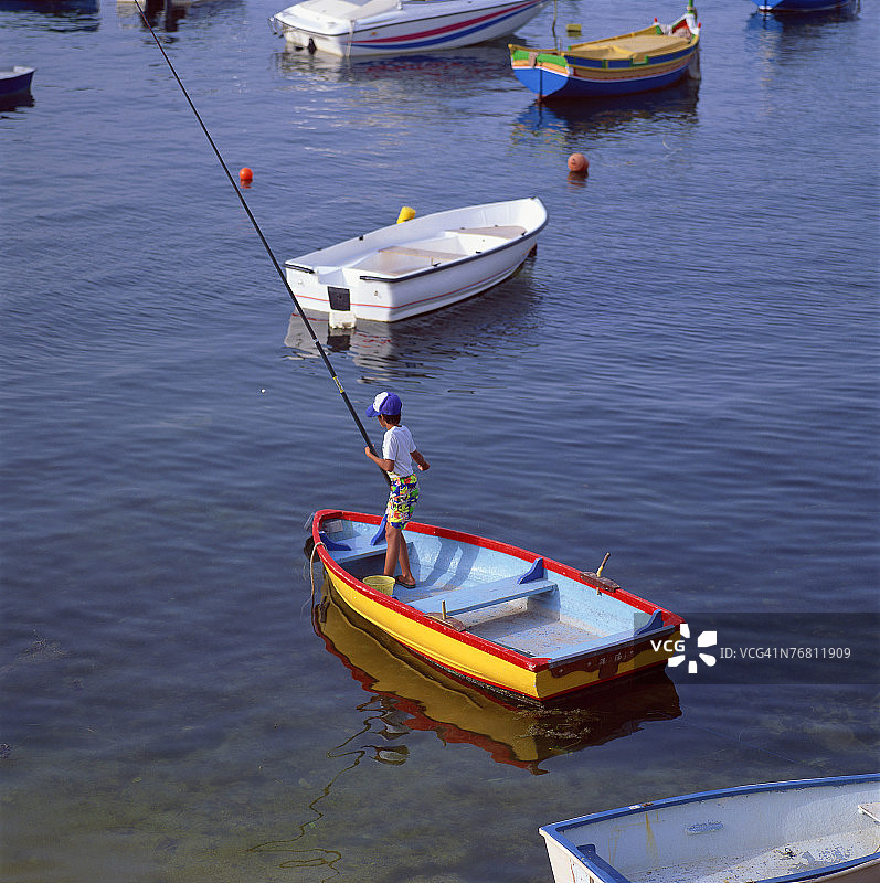 男孩在划艇上钓鱼图片素材