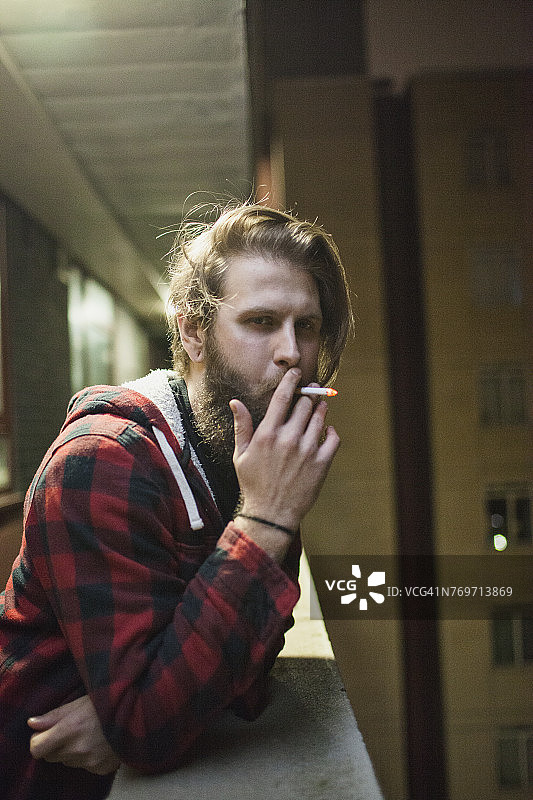 在阳台上吸烟的年轻男人图片素材