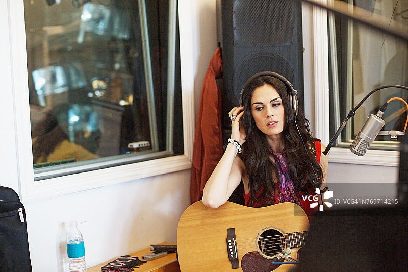 在录音室弹奏原声吉他的年轻女人图片素材