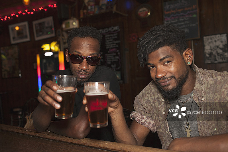 两个年轻男人在酒吧里敬酒图片素材