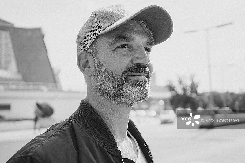 阳光明媚的一天，戴着帽子的微笑成熟男子图片素材