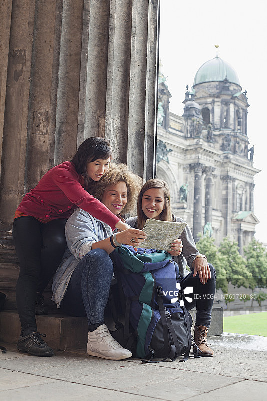 年轻女游客在德国柏林老博物馆阅读地图，背景是柏林大教堂图片素材