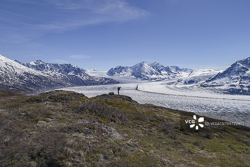 徒步旅行者在阿拉斯加帕默的克尼克冰川，看着蓝色天空下的冰川全身照图片素材