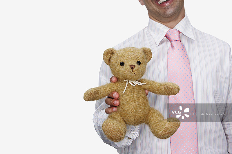 中景视角的商人抱着一只泰迪熊图片素材