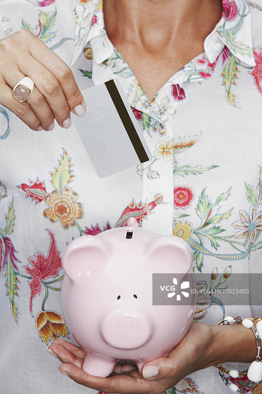 女子将硬币放入储蓄罐的腰部视角图片素材