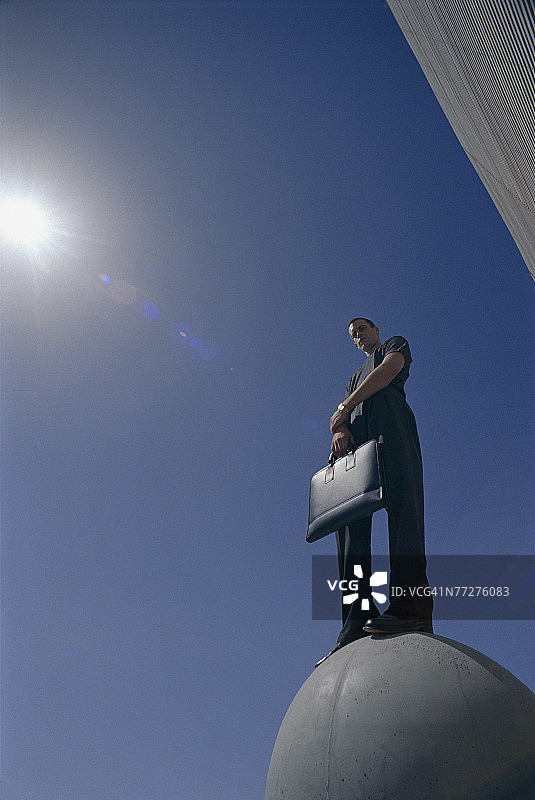 站在球体雕塑上的男人图片素材