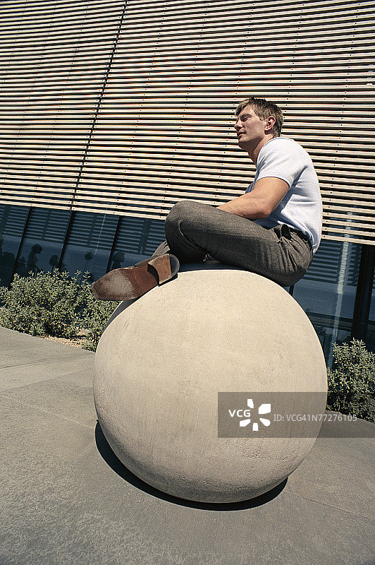 坐在球体雕塑上的男人图片素材