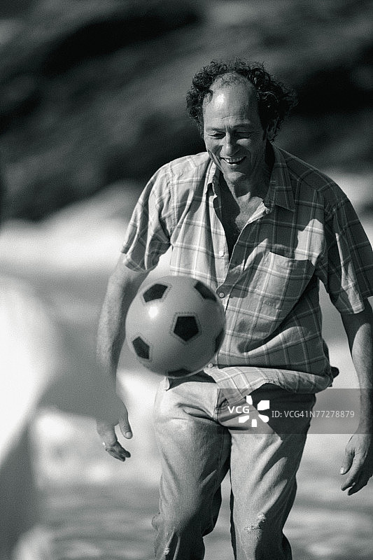 中年男人在海滩上踢足球图片素材