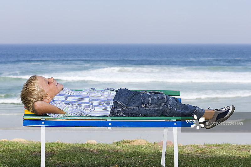 躺在海边长椅上的男孩图片素材