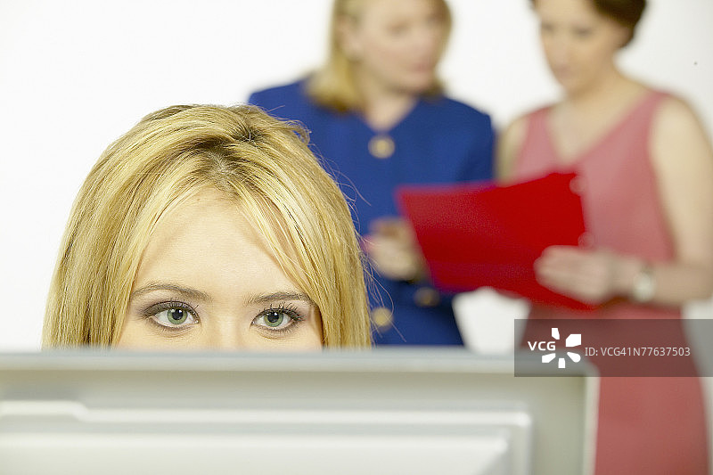 坐在电脑屏幕前的女人，背景中有两个女人图片素材