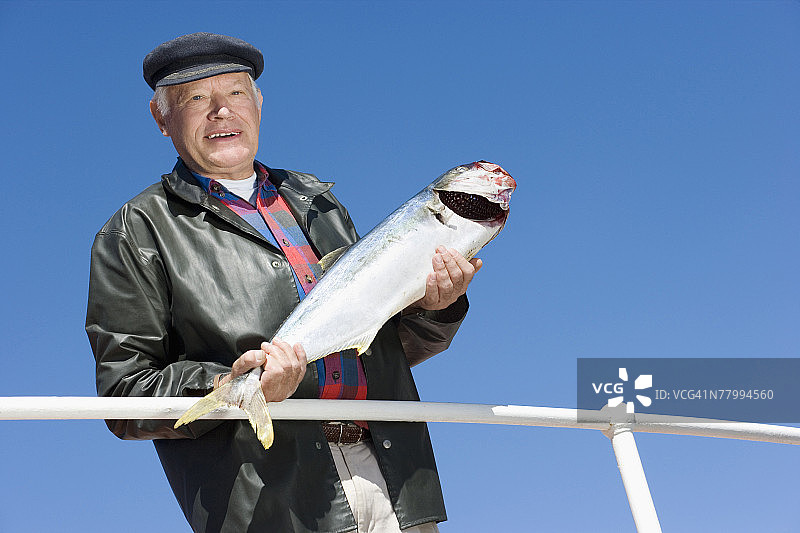 渔夫手持黄尾鱼的肖像图片素材