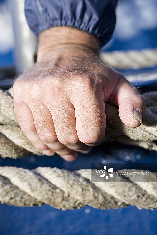 水手的手放在船的缆绳上特写图片素材