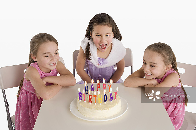 三个年轻女孩吹灭生日蛋糕上的蜡烛图片素材