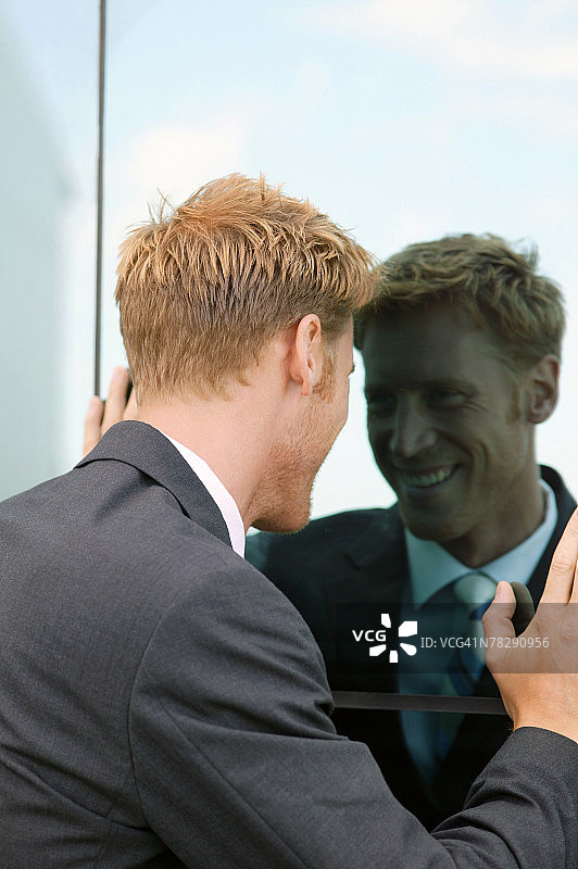 男人对着窗户里的倒影微笑图片素材