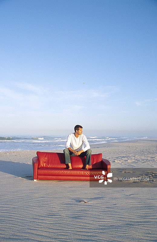男人坐在海滩的沙发上图片素材