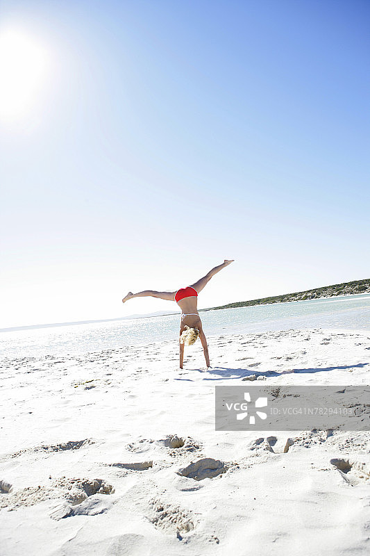 在沙滩上做侧手翻的女人图片素材