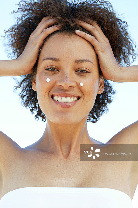 脸颊上涂抹乳液的女人图片素材