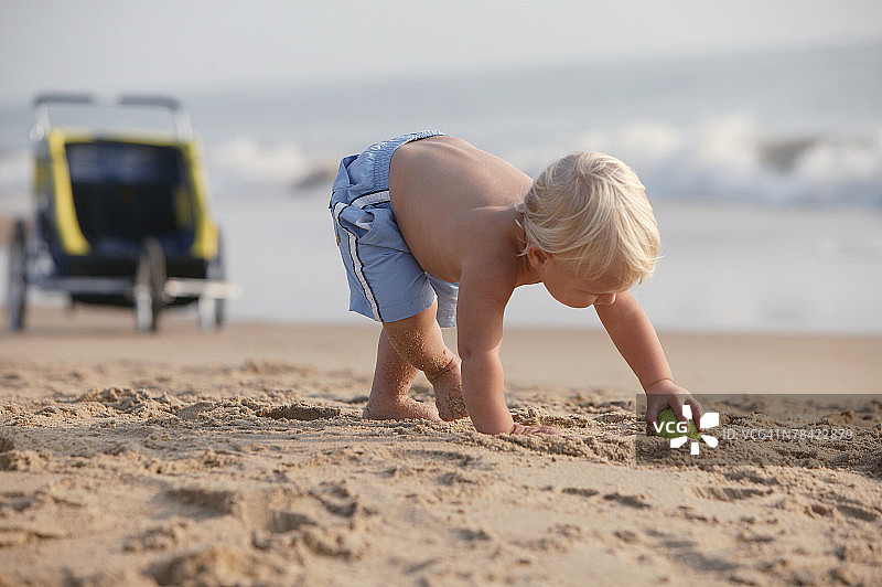 在沙滩上弯腰捡球的幼儿图片素材