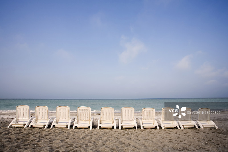 佛罗里达海湾沿岸排列着一排排白色沙滩椅，位于佛罗里达州萨拉索塔附近的隆boat键图片素材
