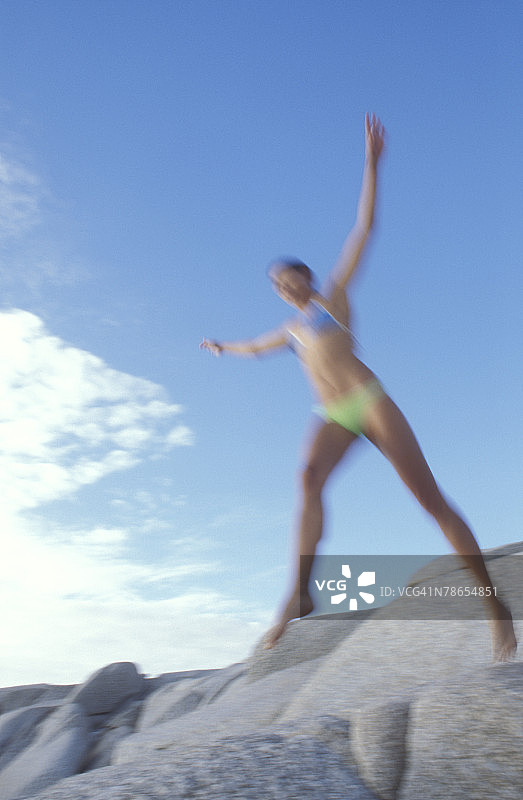 在岩石上跳跃的女人图片素材