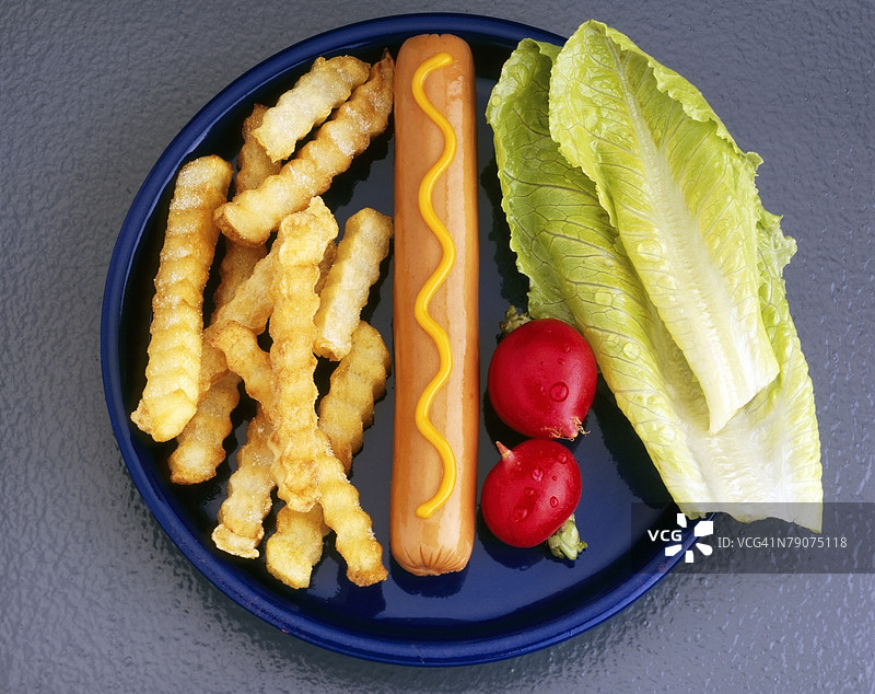 高角度视图的香肠、薯条和生菜叶放在盘子上图片素材