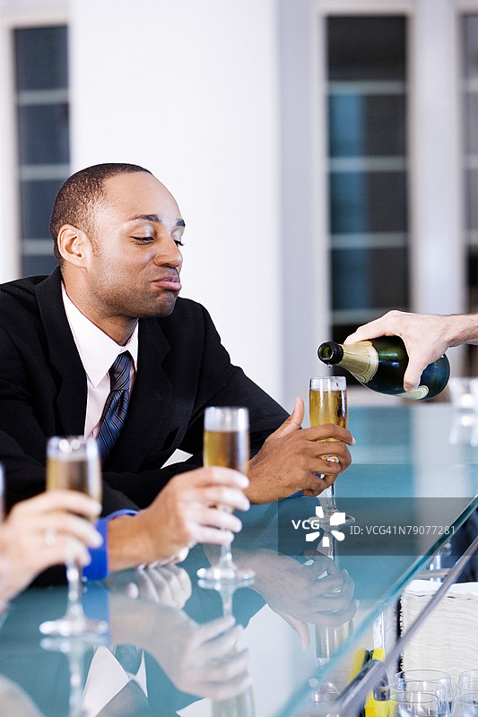 年轻男子在酒吧柜台上举着香槟杯图片素材