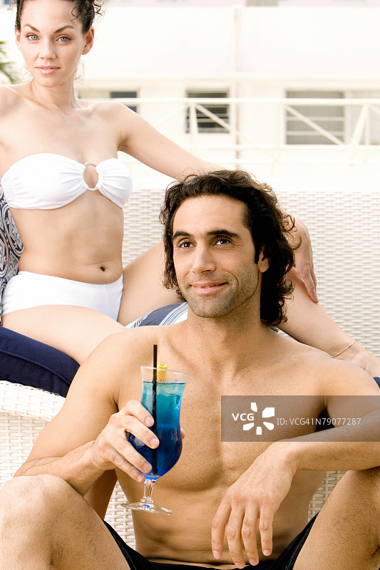 与拿着鸡尾酒的中年男人一起坐着的年轻女人肖像图片素材
