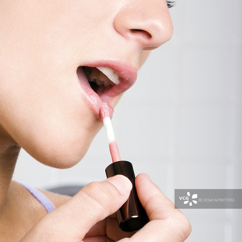 年轻女性涂口红的肖像图片素材