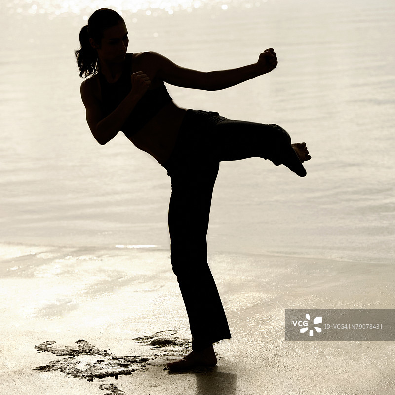 青年女人沙滩练习武术剪影图片素材