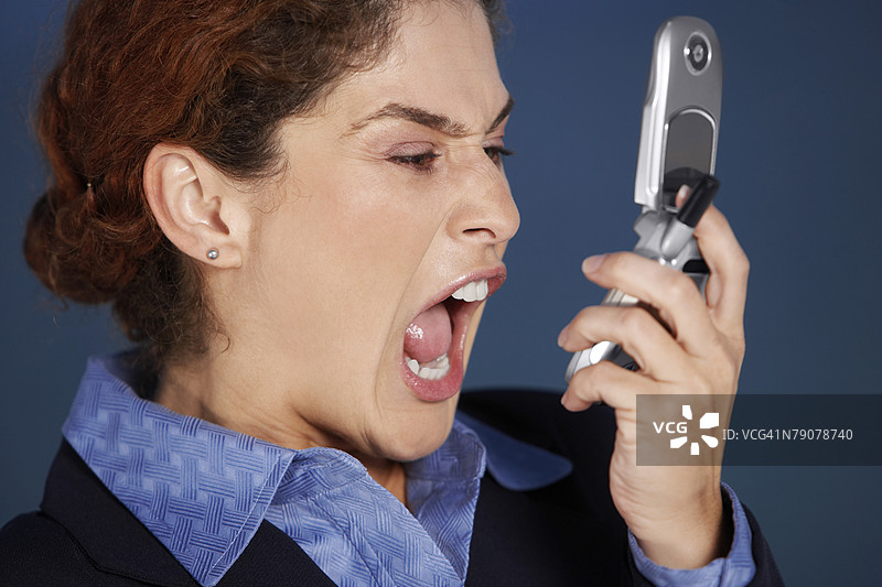 特写镜头：一位女商人手持手机大声喊叫图片素材