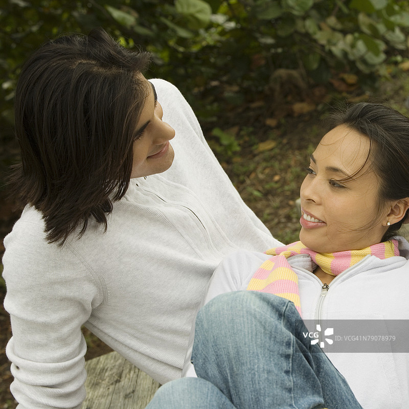 高角度视图下，一对年轻情侣微笑着互相凝视。图片素材