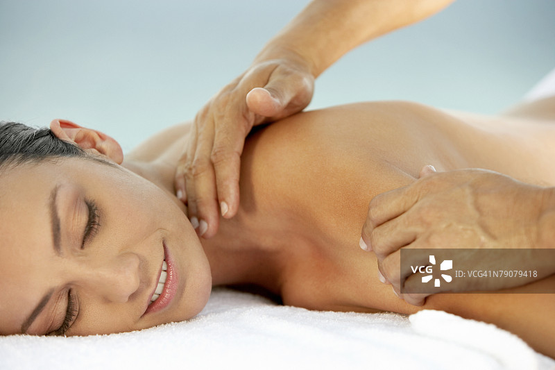 年轻女子接受肩部按摩的侧面轮廓图片素材