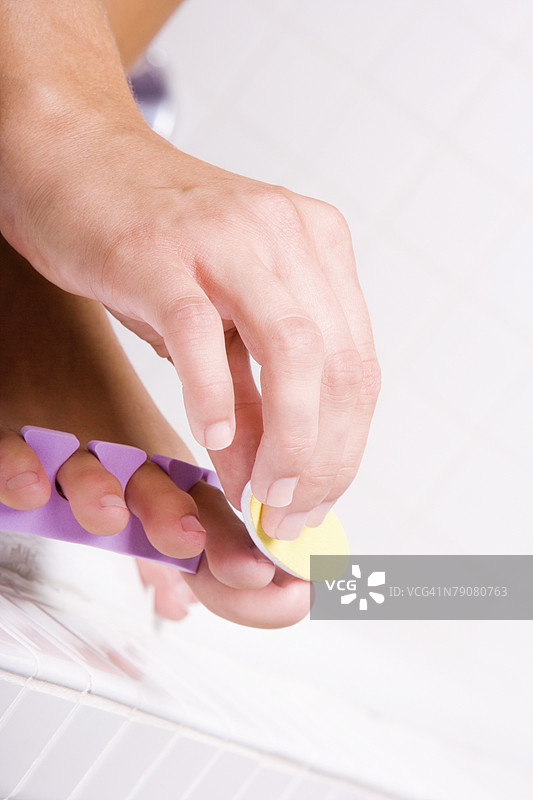 女性手部特写，正在用指甲锉修整脚趾甲图片素材