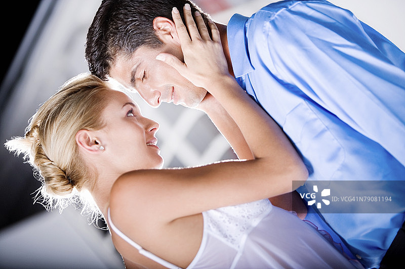 年轻女人捧着中年男人脸庞的侧面照图片素材