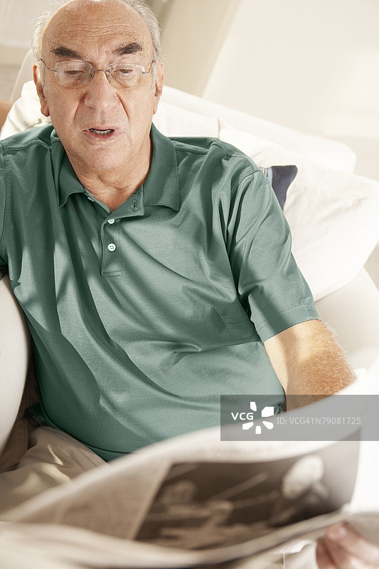 高角度视图的老年男性在阅读报纸图片素材