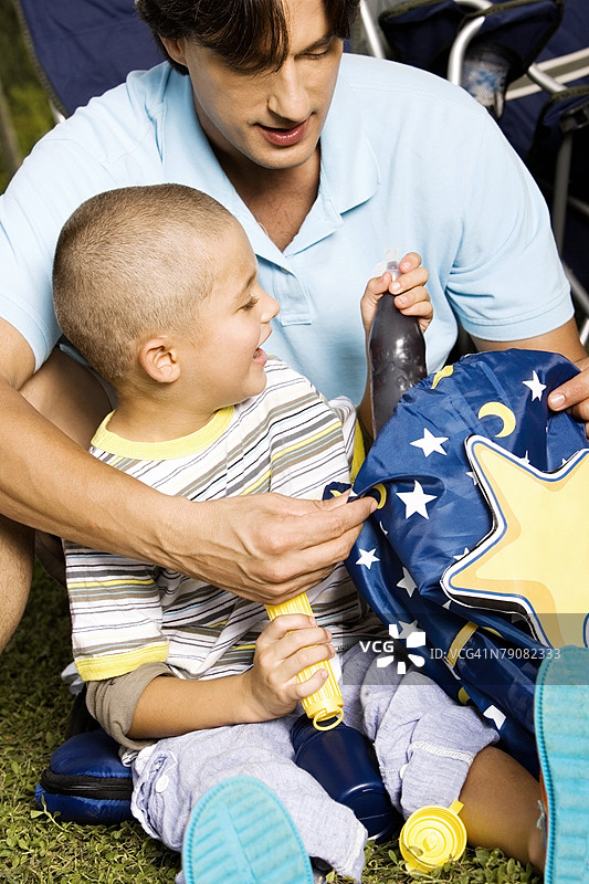 男孩与父亲坐在一起，特写镜头中男孩手握着一瓶饮料。图片素材