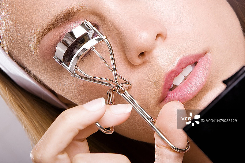 年轻女人用睫毛夹夹睫毛特写图片素材