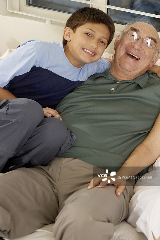 男孩和他的祖父坐在沙发上的肖像图片素材